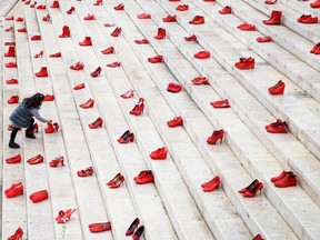A girl puts flowers at an installation of red shoes meant to denounce violence against women, in Tirana, Albania, on International Women's Day in 2021.