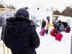 Asylum-seekers wait in line at the Roxham Road entry to Canada from Champlain, New York, last month.