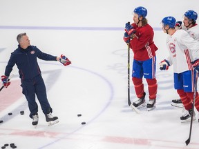 Montreal Canadiens head coach Martin St. Louis, left, speaks with Michael Pezzetta, left, Rafaël Harvey-Pinard, and Jesse Ylönen during practice in Brossard on Jan. 18, 2023.