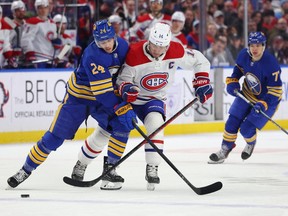 Buffalo Sabres centre Dylan Cozens (24) and Montreal Canadiens centre Nick Suzuki (14) battle for a loose puck during the first period at KeyBank Center in Buffalo on Monday, March 27, 2023.