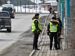 Police officers speak to a local resident at the site of the deadly truck attack which killed two people and injured nine earlier this week in Amqui on Wednesday, March 15, 2023.