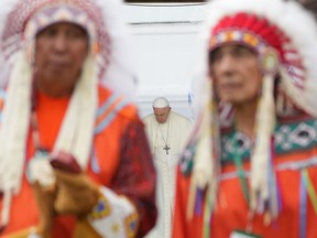 Pope Francis bows his head behind Indigenous chiefs preparing to perform a traditional dance at a ceremony in Maskwacis, Alta., on Monday, July 25, 2022. The Vatican has rejected the Doctrine of Discovery a year after Pope Francis met with Indigenous groups from Canada and delivered his first apology for the Catholic Church's role in residential schools.