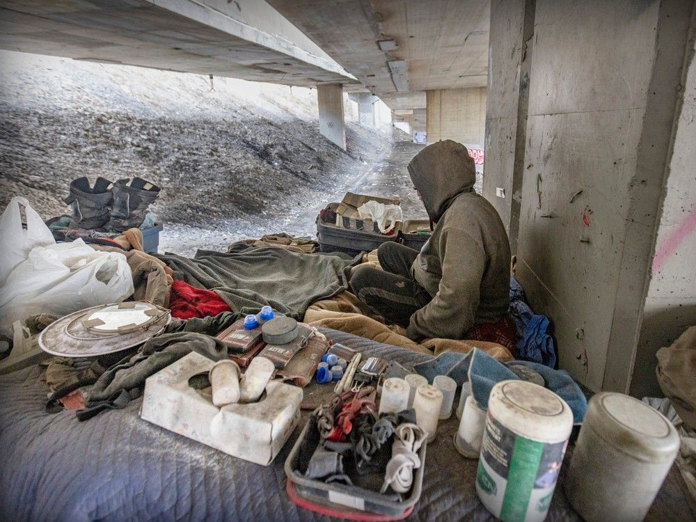 An unhoused man sits in his encampment under the Ville-Marie Expressway in Montreal on April 3, 2023. The man has lived there for two years.