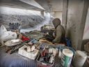 An unhoused man sits in his encampment under the Ville-Marie Expressway in Montreal on April 3, 2023. The man has lived there for two years.