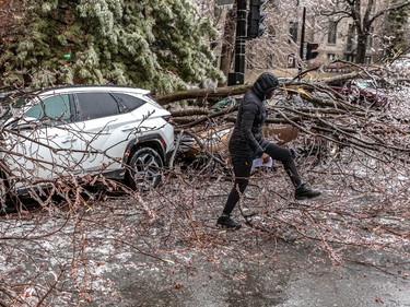 Linda Benjamin retrieved papers from her after freezing rain caused tree branches to fall on her car on Sherbrooke Street near Atwater Avenue in Montreal on Wednesday April 5, 2023.