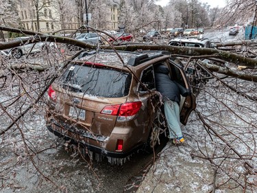 Alyssa Kuzmarov retrieves items from her car after tree branches fell on her car due to freezing rain in Montreal on Sherbrooke Street near Atwater Avenue in Montreal on Wednesday April 5, 2023.