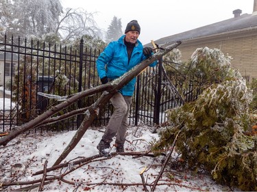 Mike Kuzmicki clears tree branches from his yard in Beaconsfield, west of Montreal Thursday April 6, 2023 after an ice storm hit the area the day before.