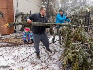 Claude Paquette, left, and his daughter Florence help neighbour Mike Kuzmicki clear tree branches from his yard in Beaconsfield, west of Montreal Thursday April 6, 2023 after an ice storm hit the area the day before.