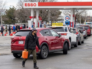A man carries a gas container back to his car at the Esso station at Fairview shopping centre in Pointe-Claire, west of Montreal Thursday April 6, 2023 after an ice storm hit the city the day before.  Motorists waited over two hours in line to pump their gas.