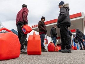 People wait in line with gas containers at an Esso station in Pointe-Claire Thursday April 6, 2023 after an ice storm hit the city the day before.  Motorists waited over two hours in line to pump their gas.