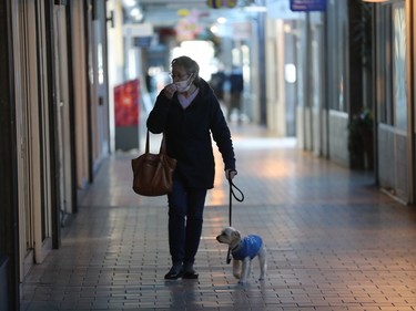 Lise Archambault and her dog Maggie walk through a dark Pointe-Claire Plaza April 7, 2023, two days after an ice storm knocked out power across the province.