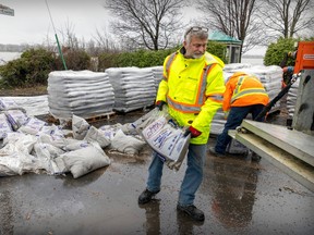 Municipal worker James Ranger loads sandbags onto a truck in the L'Île-Bizard—Ste-Geneviève borough of Montreal on April 17, 2023. Rising water levels of the Rivière-des-Prairies has prompted municipalities to take precautionary measures.