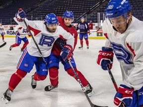 Laval Rocket left wing Joel Teasdale holds back defenceman William Trudeau as left wing Gabriel Bourque picks up the puck, right to left, during practice at Place Bell in Laval on Tuesday April 18, 2023.
