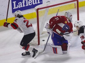 Comets' Reilly Walsh, left, celebrates after beating Rocket goalie Cayden Primeau for the opening goal Wednesday night at Place Bell.