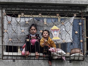 Two Palestinian children look out from a window next to a decoration showing a Ramadan lantern, in Gaza City March 30, 2023.
