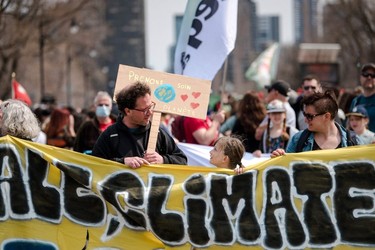 A parent and a child exchange a glance as protesters march during the Earth Day Protest on April 22, 2023, in Montreal.
