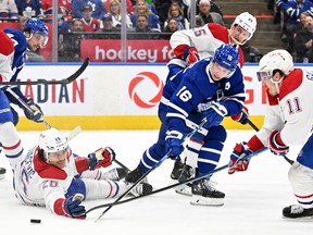 Canadiens defenceman Johnathan Kovacevic (26) uses his hand to clear the puck away from Toronto Maple Leafs forward Mitch Marner (16)at Scotiabank Arena on Saturday, April 8, 2023, in Toronto.
