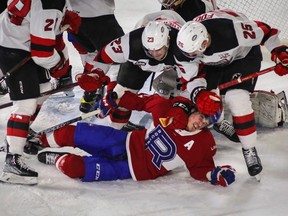 Rafaël Harvey-Pinard of the Laval Rocket is taken down by Nolan Foote, right, and Tyler Wotherspoon of the Utica Comets in the third period in the Calder Cup AHL playoff opening game at Place Bell in Laval on Wednesday, April 19, 2023.