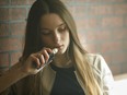 A young woman breathes from a vaping device