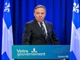 francois legault in a dark suit with quebec flags in background