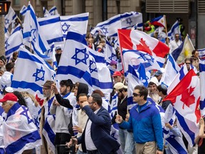Marchers carry Israel and Canada flags at a rally on a Montreal street