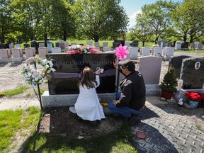 Antoinette Romano, with her husband Michael Musacchio, cleans the gravestone of their daughter Vanessa, who died in 2021, at Notre-Dame-des-Neiges Cemetery on May 14, 2023.