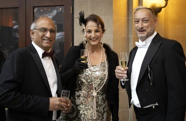 A woman is flanked by two men in a photo taken at a black-tie event
