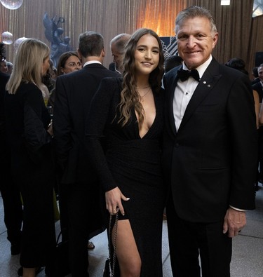 A man in a tuxedo is photographed with his daughter at a party