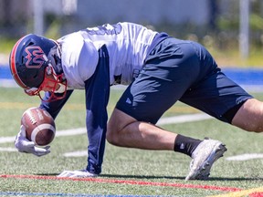 Greg Ellingson holds a football just above the turf