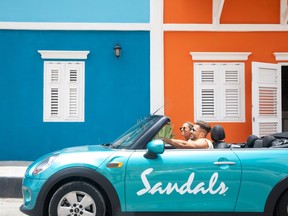 A blue convertible mini cooper with a sandals logo