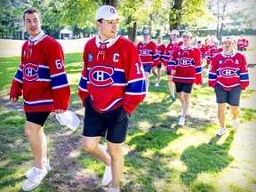 Nick Suzuki and teammates walk through a park in shorts and Canadiens jerseys