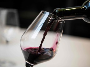 a sommelier pours a glass of red wine