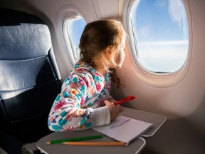 Child drawing picture with crayons in airplane.