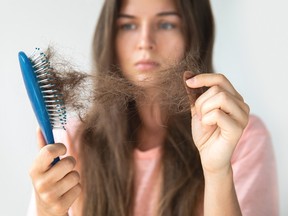 Young woman is upset because of hair loss.