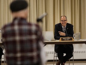Dorval Mayor Marc Doret in a suit smiling at a resident during a council meeting