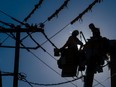 Workers fix hydro lines, suspended in a bucket.