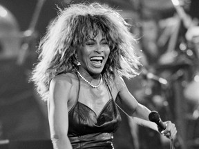 Tina Turner smiles holding a microphone