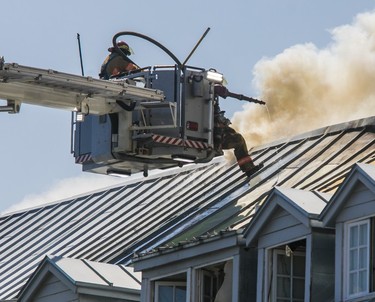 A firefighter kicks on the roof while battling a blaze at the former Monastère du Bon-Pasteur in Montreal on May 26, 2023.