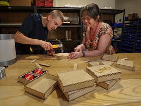 a woman and man work together to build small boxes for card games