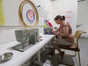 A woman uses a sewing machine with a second sewing machine in the foreground