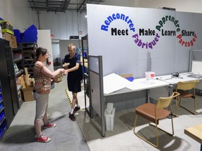 A woman and man stand near a sign that says meet, make, learn, share