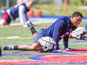 Avery Williams stretches on the field next to a helmet