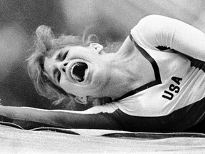 A gymnast screams in pain lying on the ground, a hand near her knee