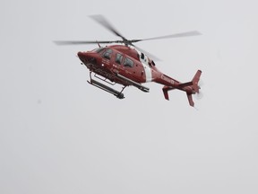 A Canadian Coast Guard helicopter patrols the river looking for two missing firefighters after major spring floods hit the Charlevoix region, Tuesday, May 2, 2023, in Baie-St-Paul, Que.