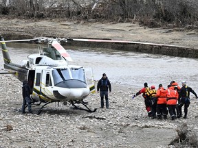 Rescuers carry the body of one of the two missing firefighters to a helicopter, Wednesday, May 3, 2023  in Baie-Saint-Paul, Que. Quebec provincial police say they have found a body in the community northeast of Quebec City where two volunteer firefighters were swept away by floodwaters during a rescue mission on Monday.