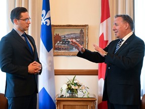 Pierre Poilievre and François Legault in a room with Canadian and Quebec flags