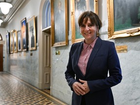 Nathalie Roy stands in front of a hallway with paintings on the walls