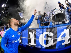 CF Montréal goalkeeper Jonathan Sirois raises his arm and smiles toward a large bell in the stands, with fans cheering amid smoke