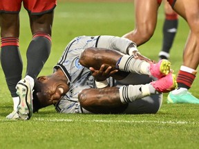 Romell Quioto grimaces holding his left leg on the soccer pitch