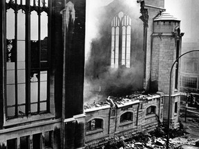 Smoke rises from the remains of a destroyed church in a black and white photo